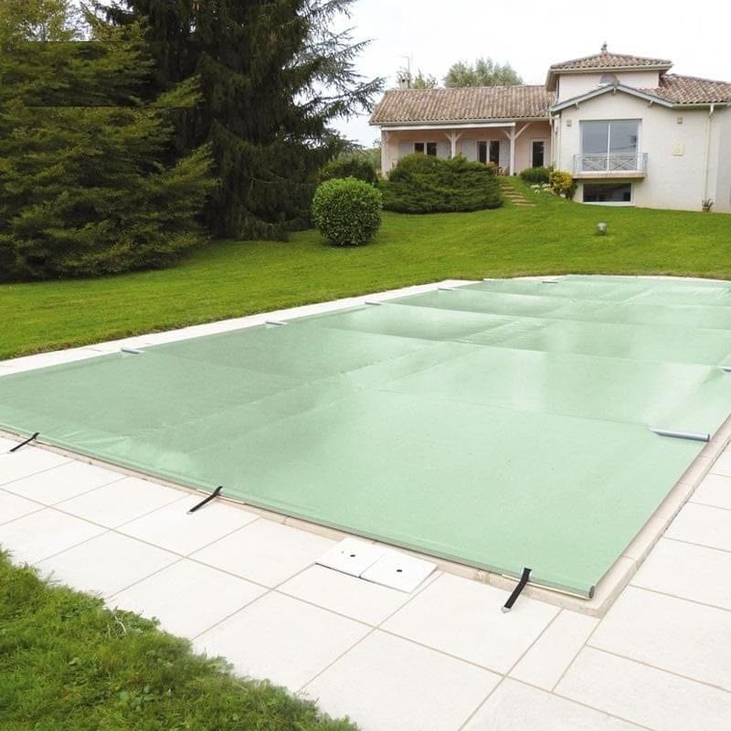 Couverture de piscine verte tendue dans un jardin