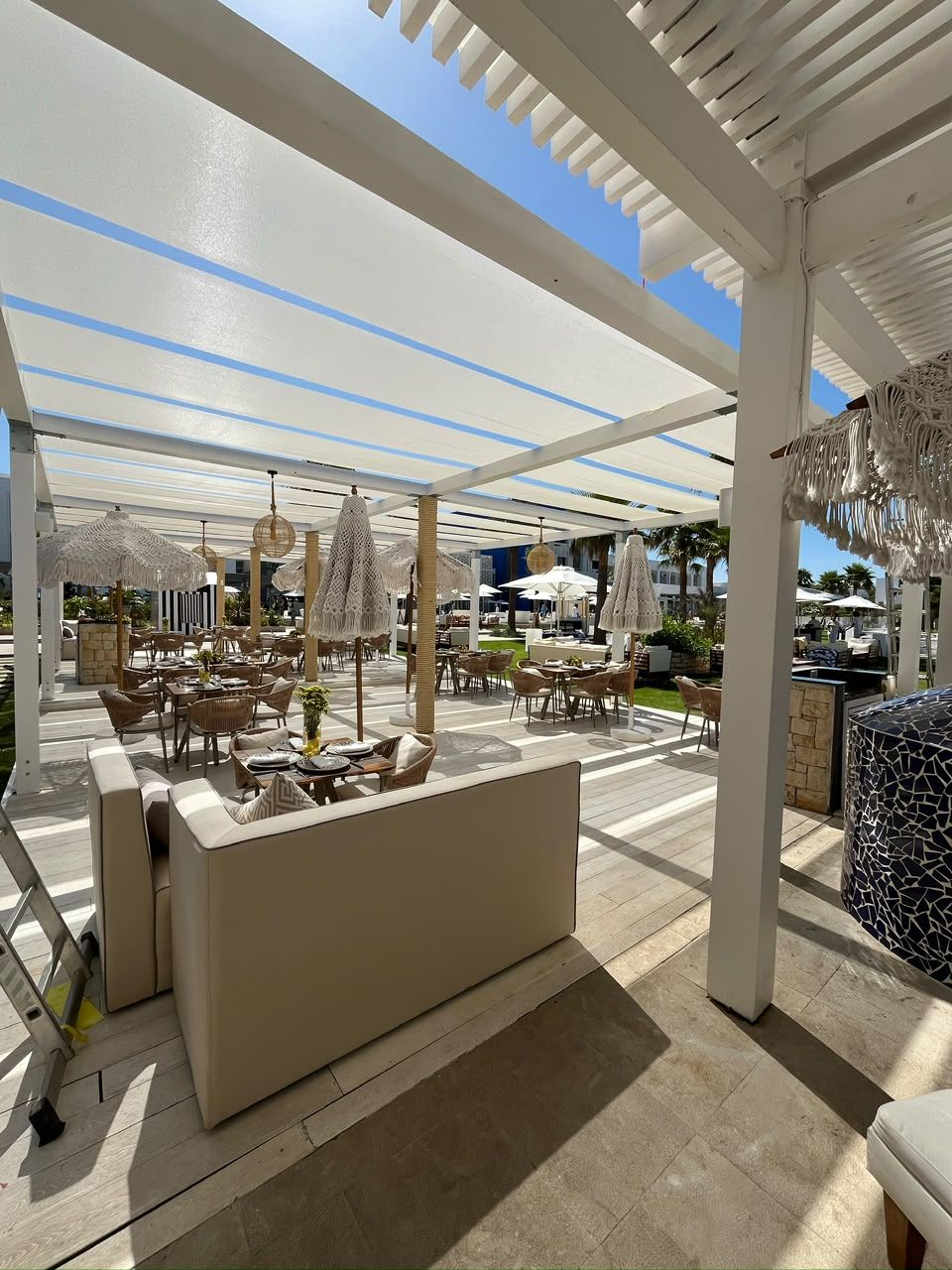 Pergola à lames blanches sur une terrasse de restaurant
