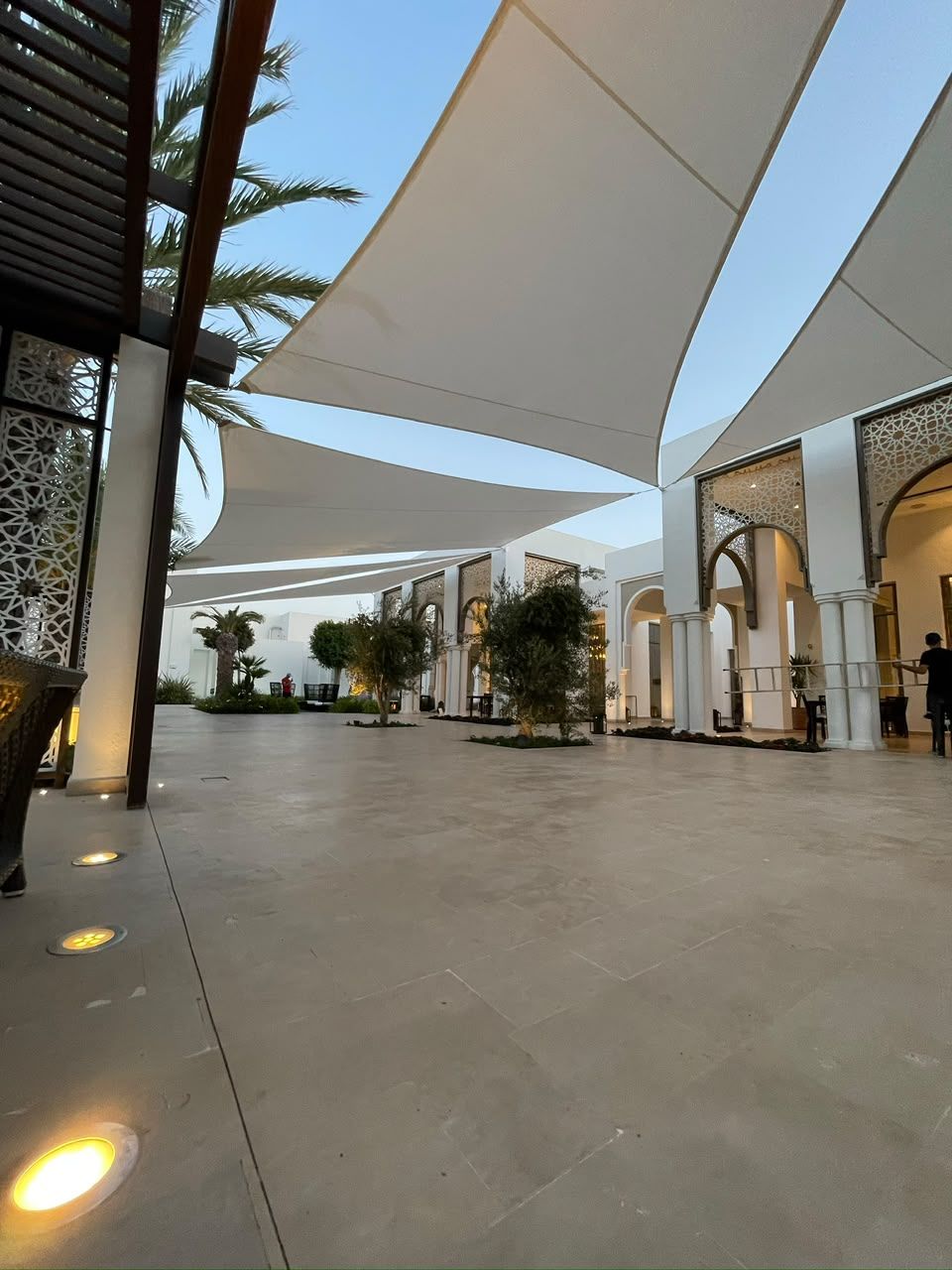 Voiles d'ombrage blanches et façade à arcades